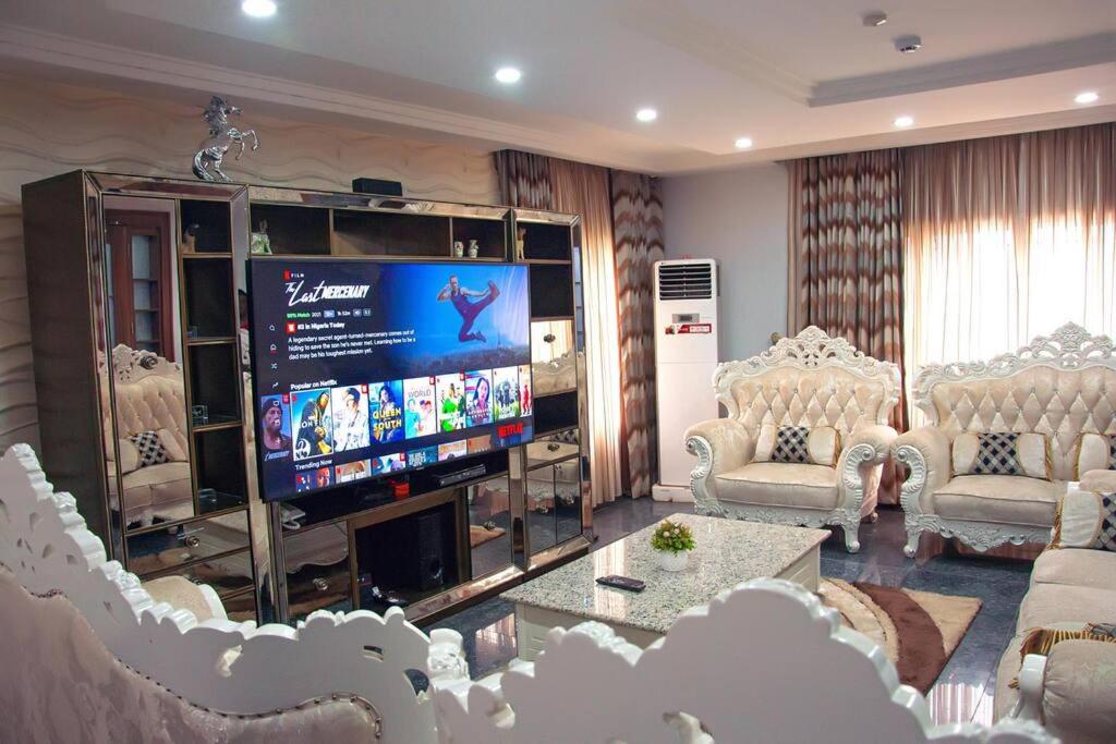 a living room with chairs and a large screen television at Modern Luxury Home W/ 24H Power Wi-Fi & Security in Abuja