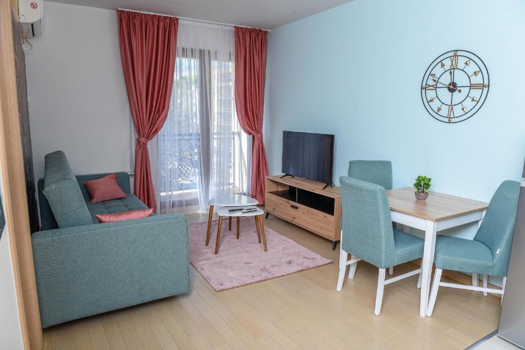 een woonkamer met een tafel en stoelen en een televisie bij Flatiron Apartments Skopje in Skopje