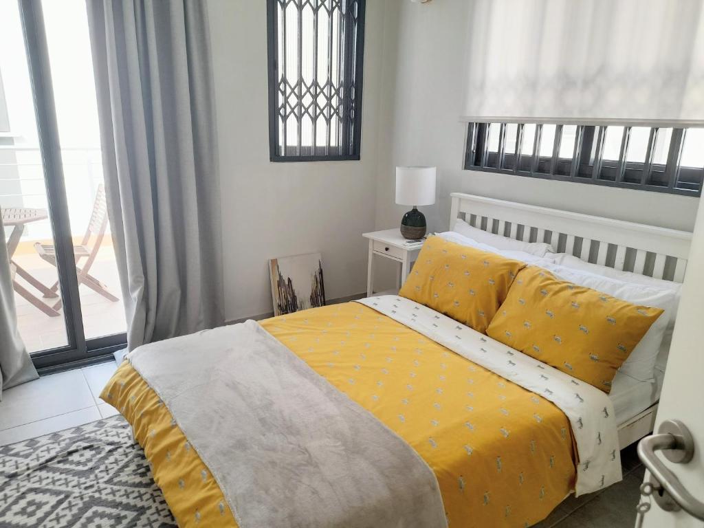 ein Schlafzimmer mit einem Bett mit gelber Bettwäsche und einem Fenster in der Unterkunft Beautiful Home - 2 Double Rooms in Accra