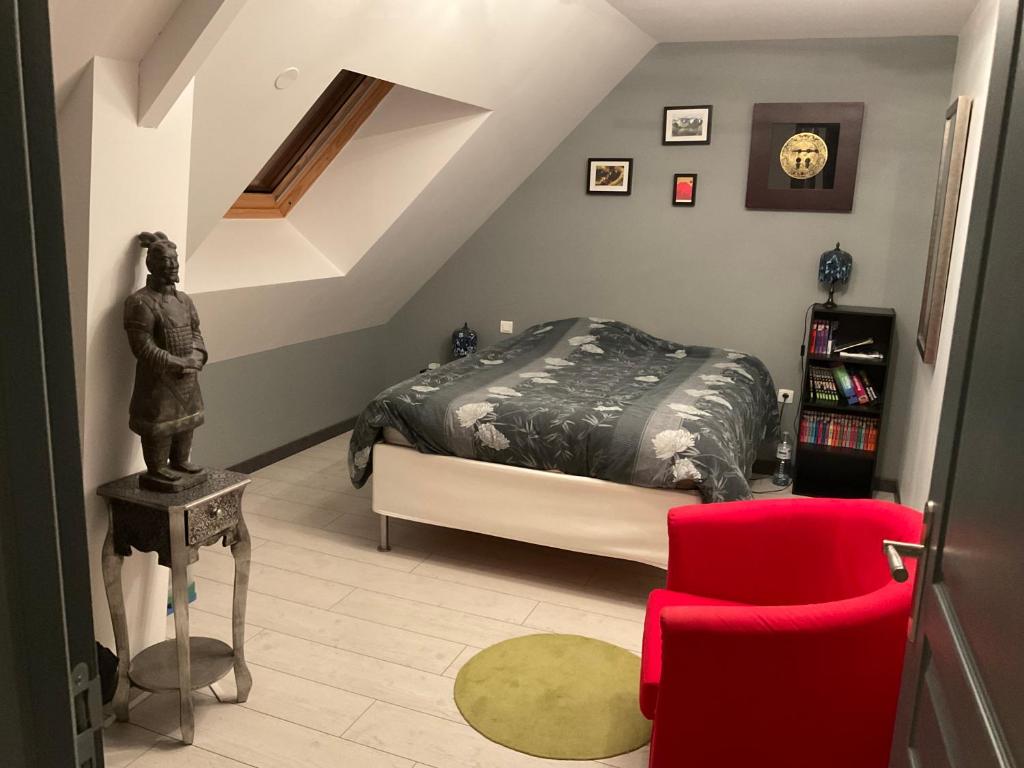 1 dormitorio con 1 cama y 1 silla roja en CHAMBRES 24h DU MANS OU LE MANS CLASSIC OU GP MOTO, en Saint-Gervais en-Belin