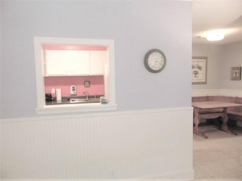 Una cocina con una ventana y un reloj en la pared. en D7 screened porch welcoming and cozy Downstairs neat and ready for your arrival, en Mallory Park