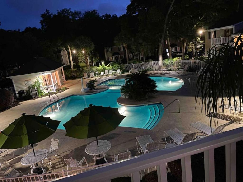 a swimming pool with chairs and umbrellas at night at c2 Ocean Walk Pool view village area cozy Upstairs sleeps 5 1 king bed two sleepers in Mallory Park