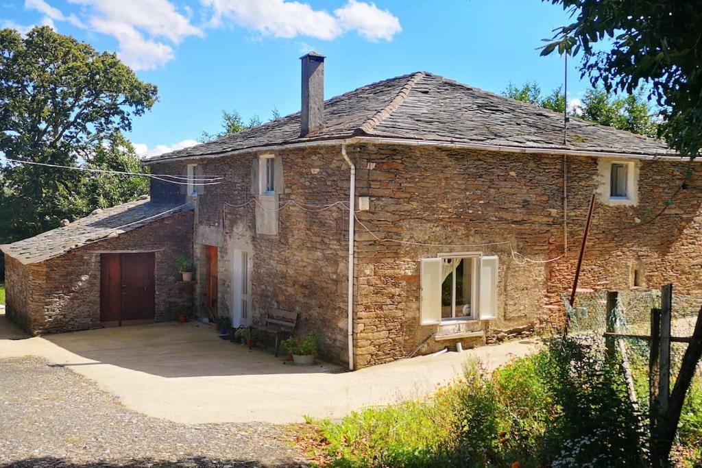 una antigua casa de ladrillo con una gran entrada en Casa O Coto, en Grañas