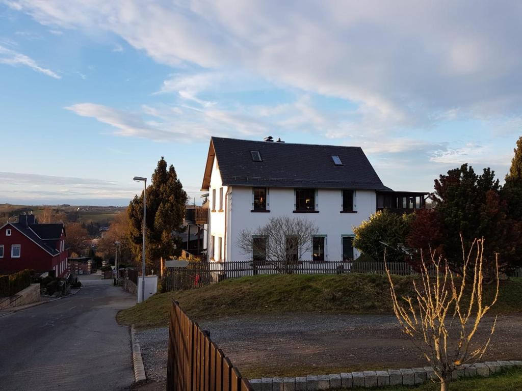 una casa blanca con techo negro en una colina en Familienfreundliche Ferienwohnung Erzgebirge en Schneeberg