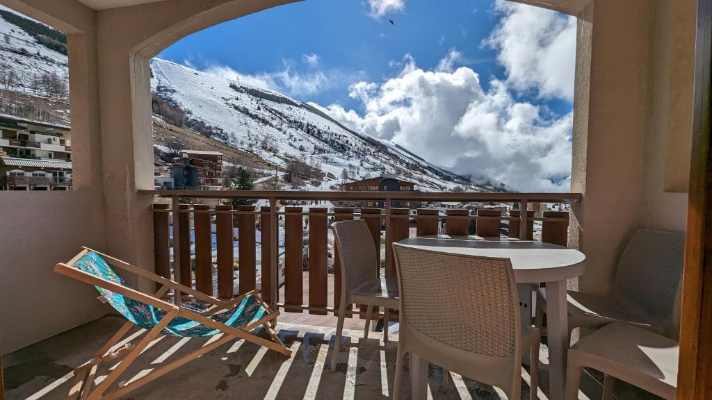 un balcón con mesa, sillas y una montaña nevada en Au pied des pistes avec panorama sur les montagnes en Les Deux Alpes