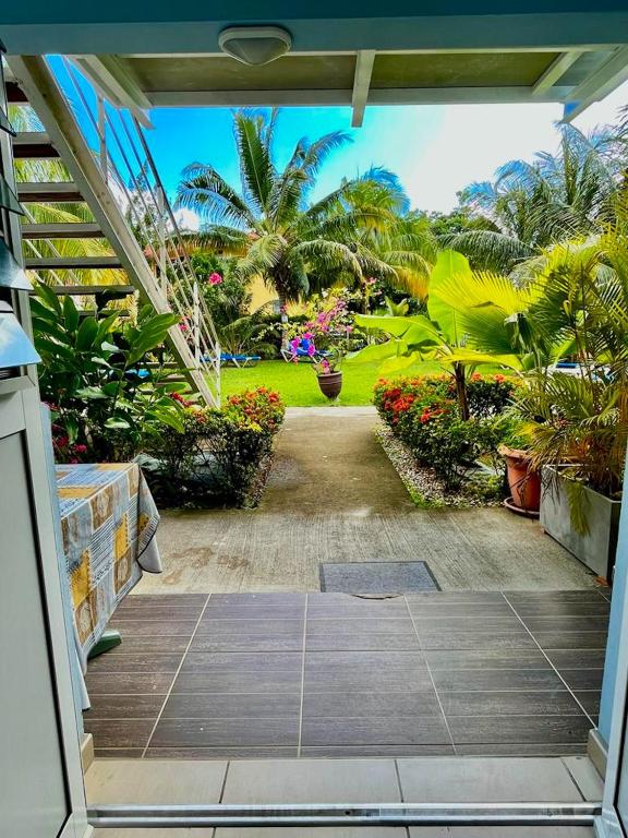une porte ouverte sur un jardin planté de palmiers et de fleurs dans l'établissement Appartement d'une chambre a Sainte Luce a 20 m de la plage avec vue sur la mer jardin clos et wifi, à Sainte-Luce
