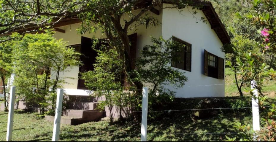 una casa blanca con una valla delante en Casa de Campo no Parque Estadual da Serra do Mar en São Luiz do Paraitinga