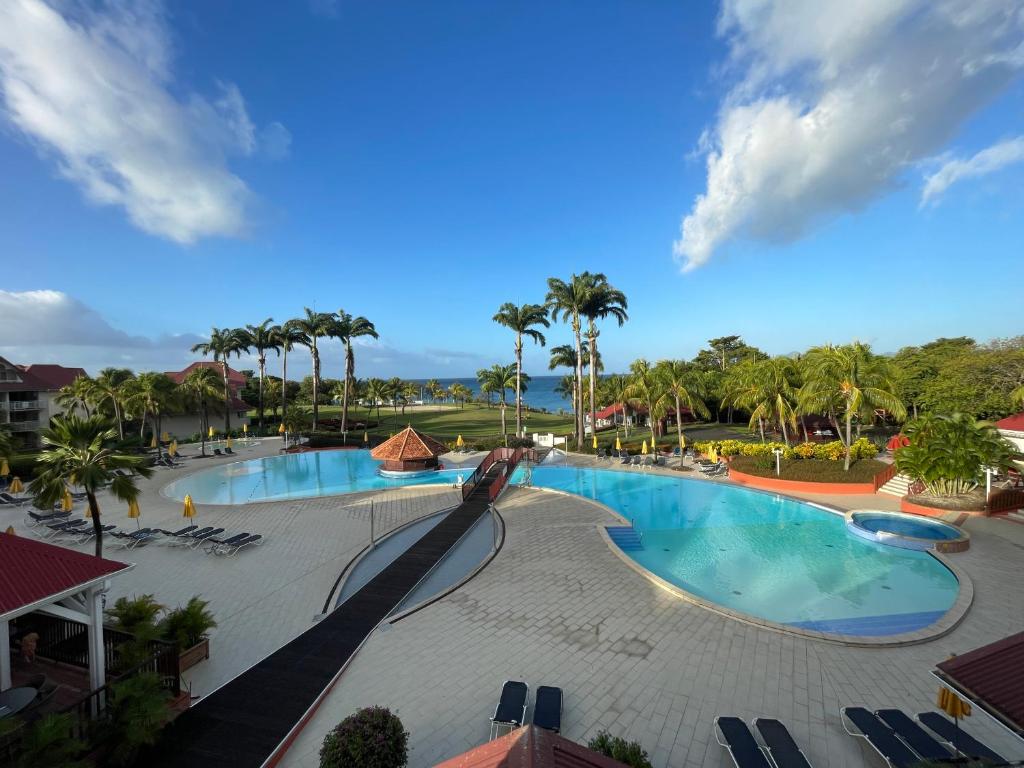 Blick auf den Pool in einem Resort mit Palmen in der Unterkunft Appartement Madinina 6 personnes vue sur mer dans village vacances in Sainte-Luce