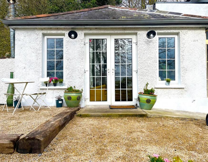 una casa bianca con una porta e due piante in vaso di Killenard Kottage, Killenard, Laois a Killenard