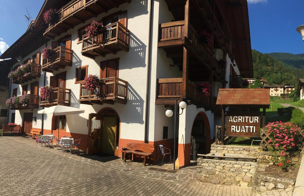 un edificio con balcones, mesas y sillas en una calle en Agritur Ruatti, en Rabbi