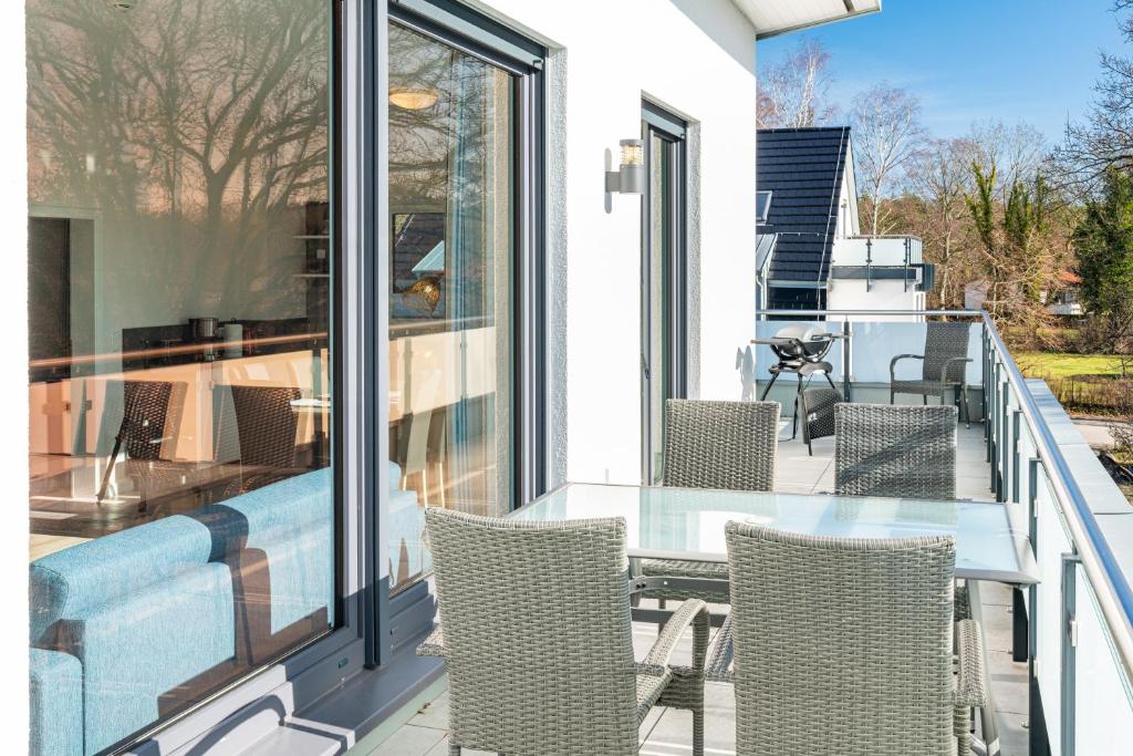 a balcony with a glass table and chairs at Kehrwieder Zinnowitz Ferienwohnungen mit Sauna in Zinnowitz