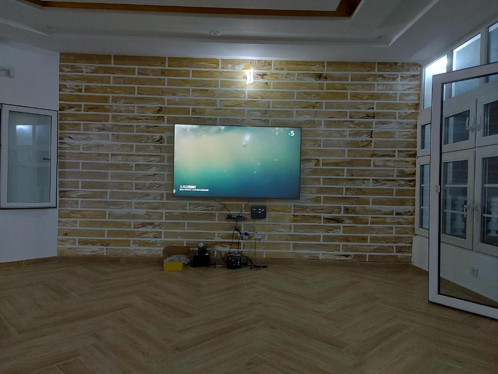a room with a brick wall with a flat screen tv at Villa Eloy in Lomé