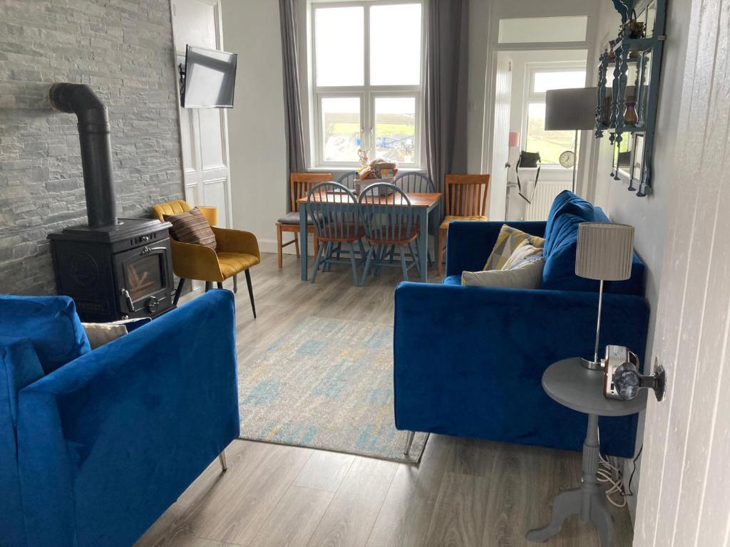 sala de estar con 2 sofás azules y estufa de leña en Glenhill - Newly renovated in a unique location, en Belmullet