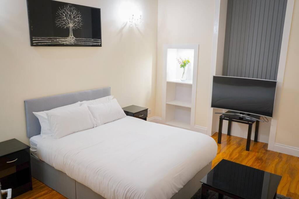 a bedroom with a white bed and a flat screen tv at Glasgow - 2 Bedroom Apartment in Glasgow