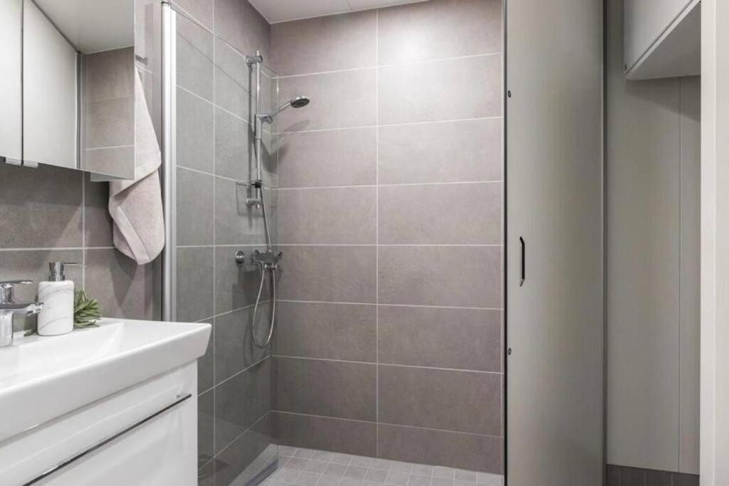 a bathroom with a shower and a white sink at New condo with free parking 10 min from Helsinki Airport in Vantaa