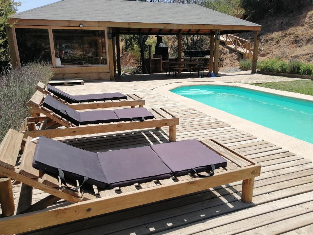 une terrasse avec des chaises longues à côté d'une piscine dans l'établissement lliulliunewen, à Limache