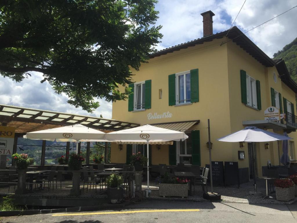 budynek ze stołami i parasolami przed nim w obiekcie Hotel Bellavista Cavigliano w mieście Cavigliano