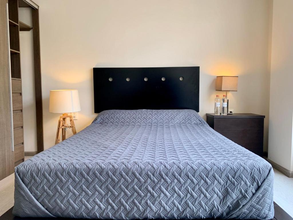 ein Schlafzimmer mit einem Bett mit blauer Decke und 2 Lampen in der Unterkunft Mexico City MondoMexico Deluxe apartments in Mexiko-Stadt