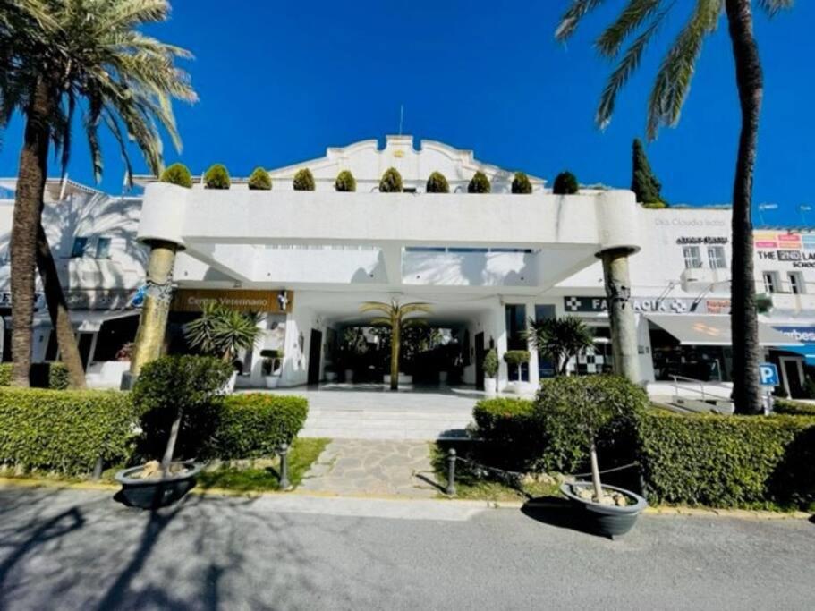 a white building with palm trees in front of it at Apart Milla de Oro Marbella in Marbella