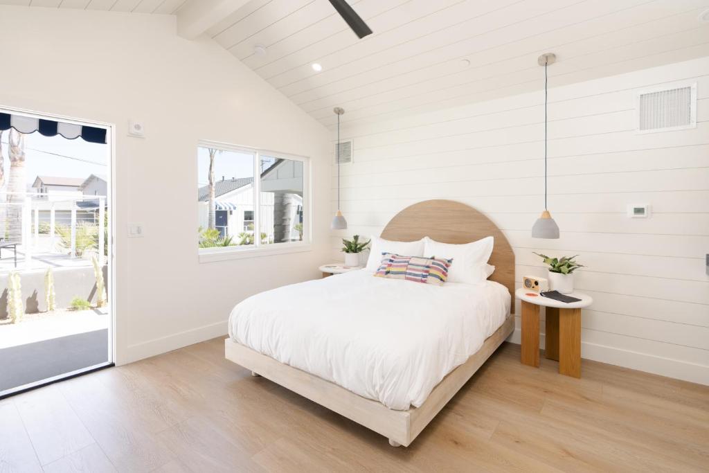 a white bedroom with a bed and a window at The Pacific Motel in Cayucos