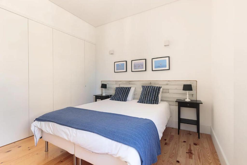 1 dormitorio con 1 cama blanca grande y 2 almohadas azules en Canto da Praça - No coração do centro de Aveiro, en Aveiro