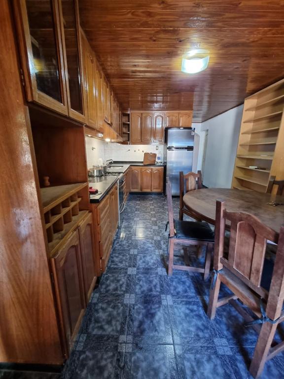 una cocina con armarios de madera, mesa y sillas en Casa Nina San Rafael en San Rafael