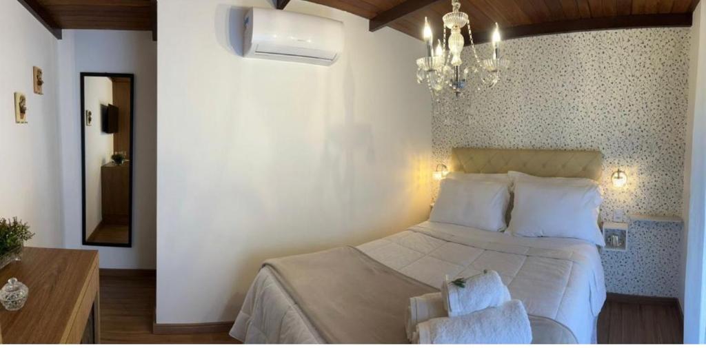 a bedroom with a bed and a chandelier at Pousada Dulce Ville in Domingos Martins