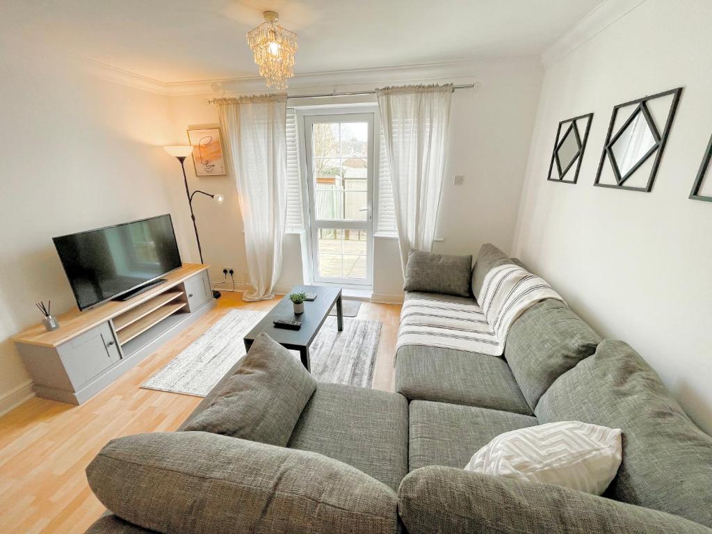 a living room with a couch and a television at Bright and modern 4-bed townhouse with garden near town centre in Kent