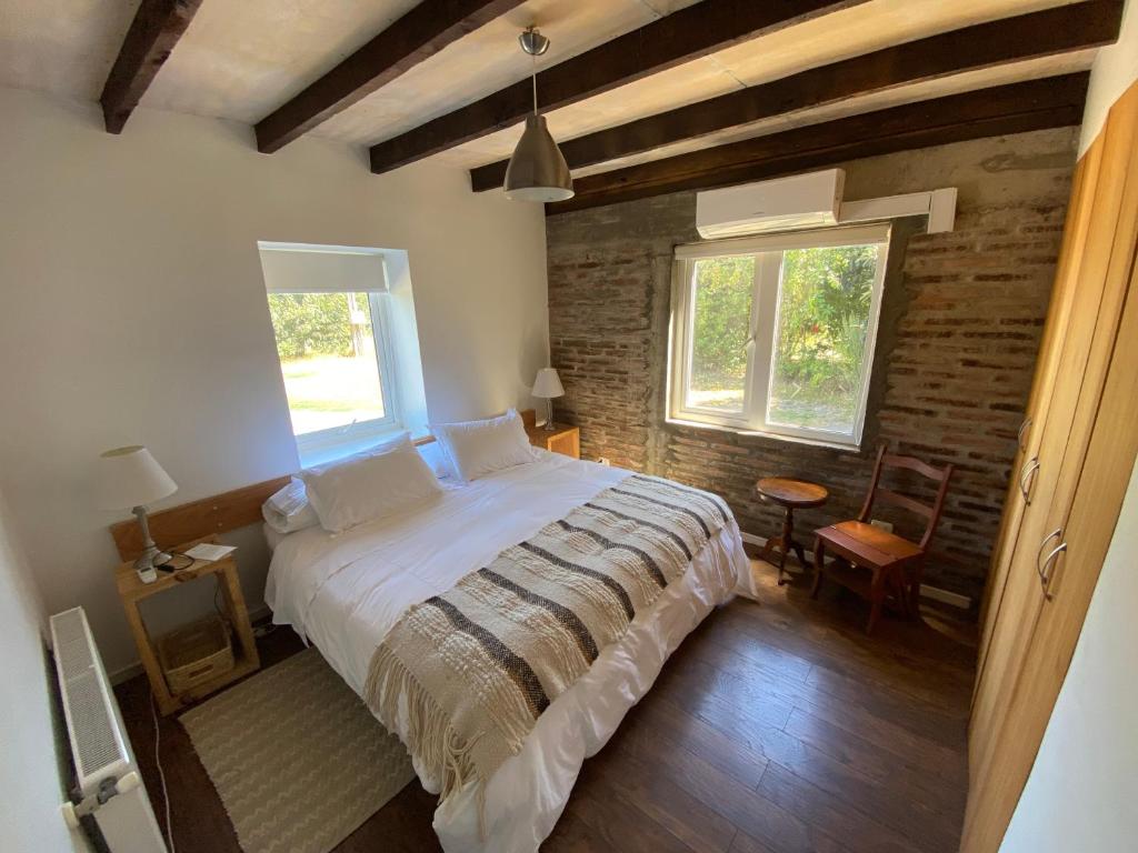 a bedroom with a large bed and two windows at Family Orchard Bed & Breakfast in Angol