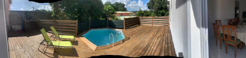 a swimming pool on a wooden deck with chairs at StephAppart in Le Robert