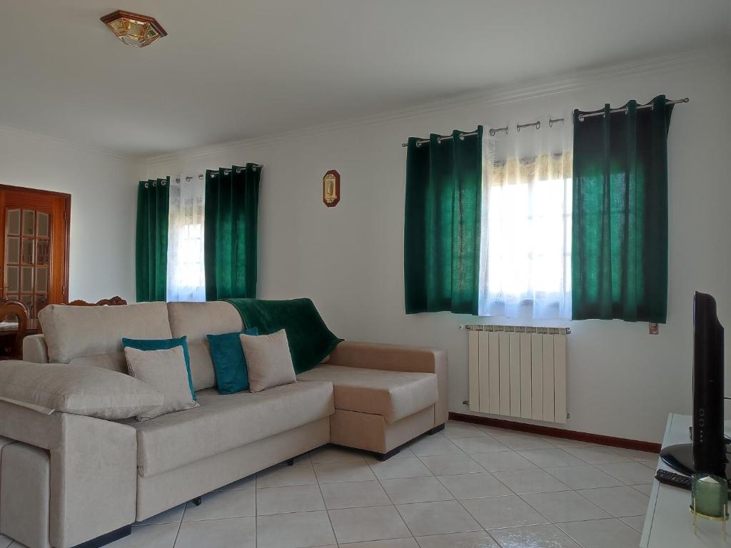 a living room with a couch and green curtains at Casa das Camélias in Viseu