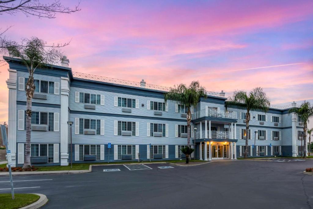 ein großes weißes Gebäude mit Palmen auf einem Parkplatz in der Unterkunft Best Western Colonial Inn in Selma