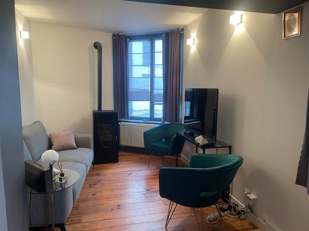 een woonkamer met een bank en stoelen en een tv bij Le cocon tournaisien in Tournai