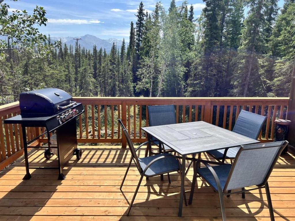 a grill on a deck with a table and chairs at Denali National Park 2 King Bedroom Hideaway with Amazing Views in Healy