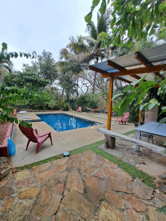 einen Pool mit einem roten Stuhl und einem Picknicktisch in der Unterkunft Guesthouse Casa Avi Fauna in Ocotal