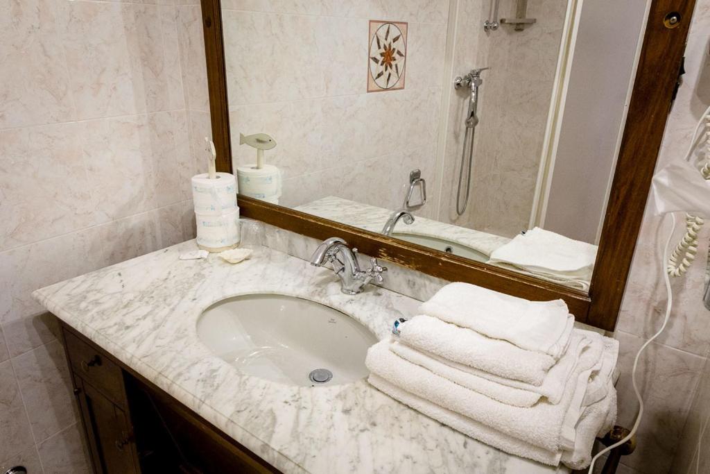 a bathroom with a sink and a mirror and towels at Hotel Marina in Monterosso al Mare