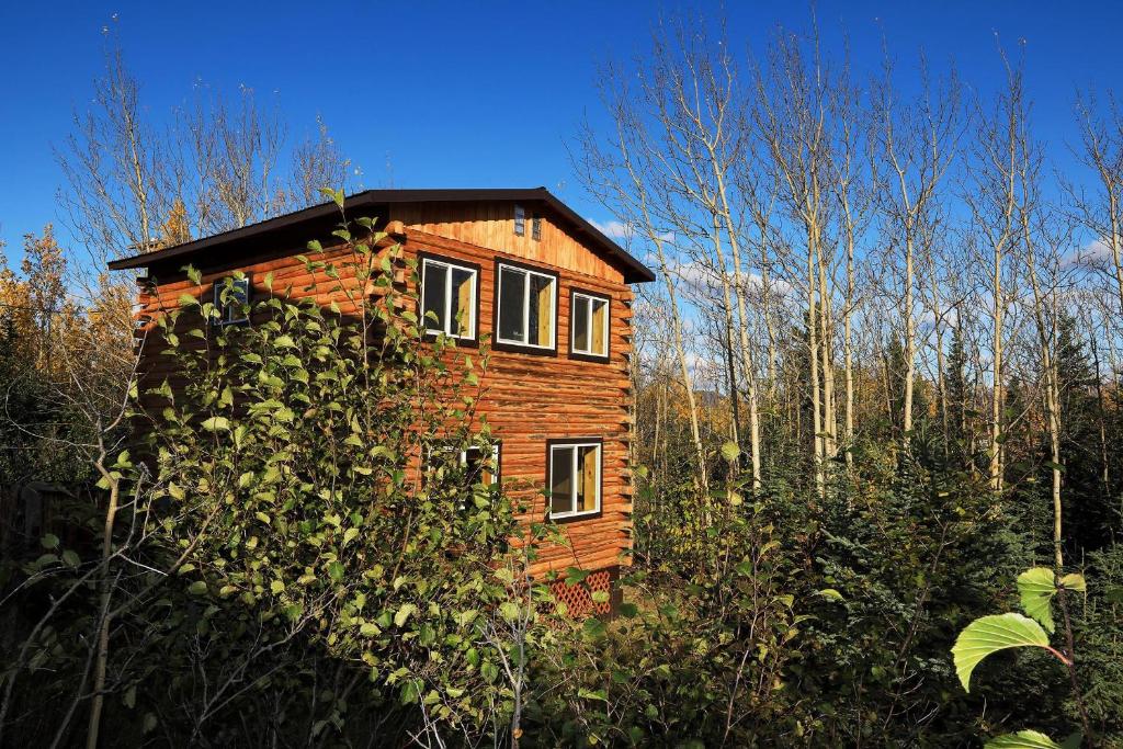 Denali Park View Family Log Cabin في McKinley Park: منزل خشبي في وسط غابة