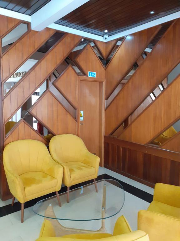 Zimmer mit zwei gelben Stühlen und einem Glastisch in der Unterkunft Hotel SQUARE in Sertã