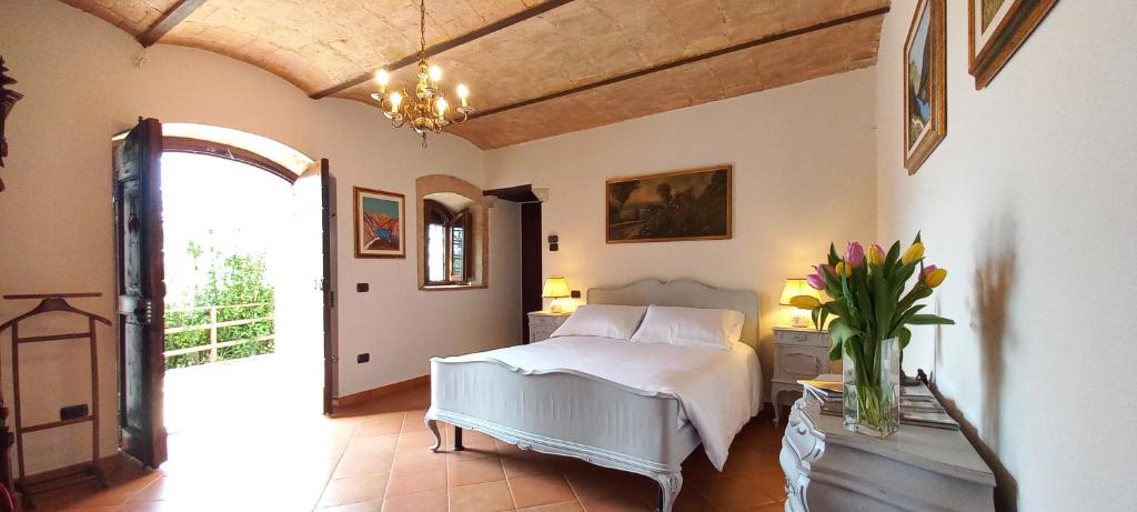 ein Schlafzimmer mit einem Bett und einer Vase aus Blumen auf einem Tisch in der Unterkunft Domus Antiqua Bed & Breakfast in Spello