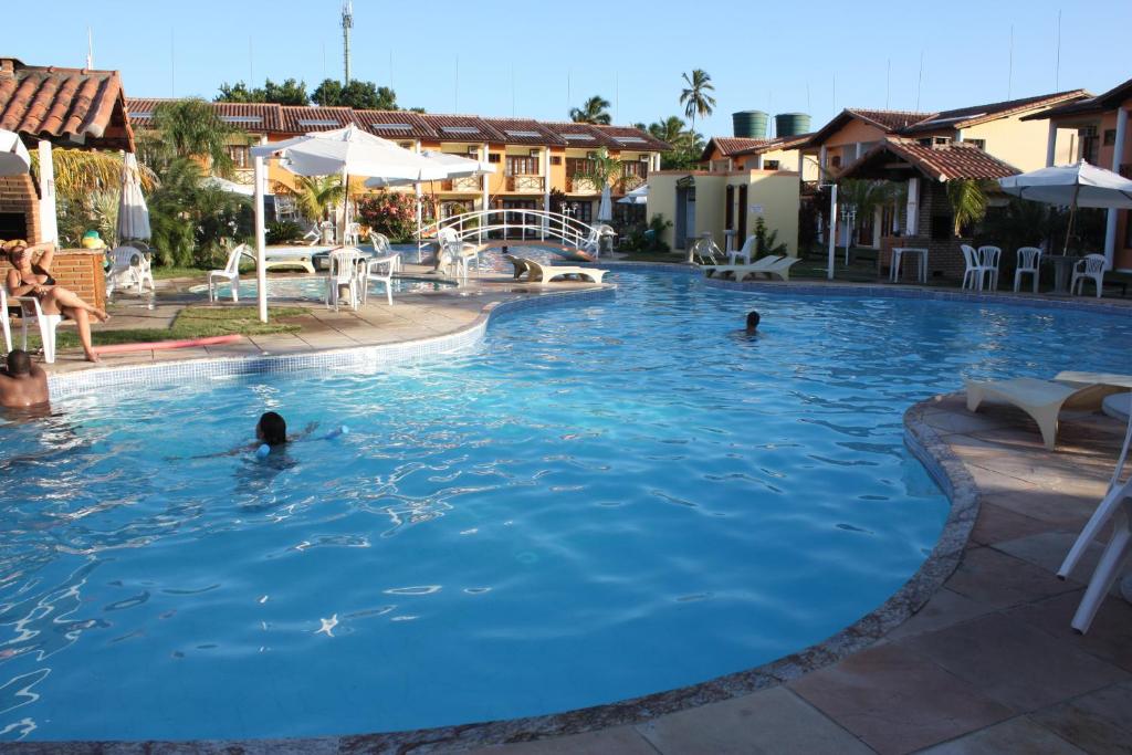 uma piscina num resort com pessoas na água em Paraiso Moradas em Porto Seguro