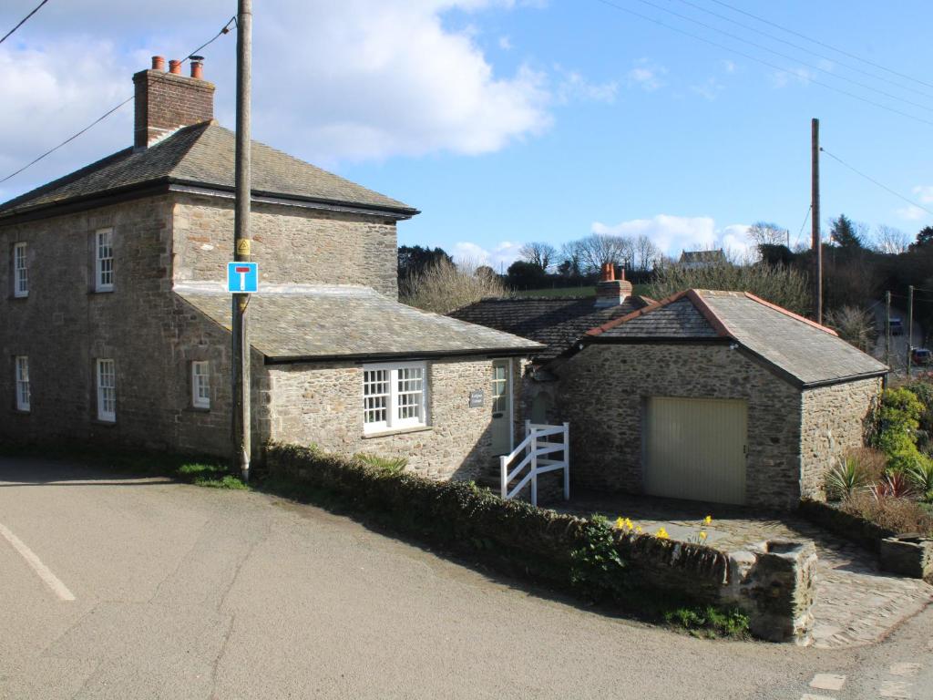 an old stone house with a garage in a street at Ludgvan Cottage in Gorran Haven