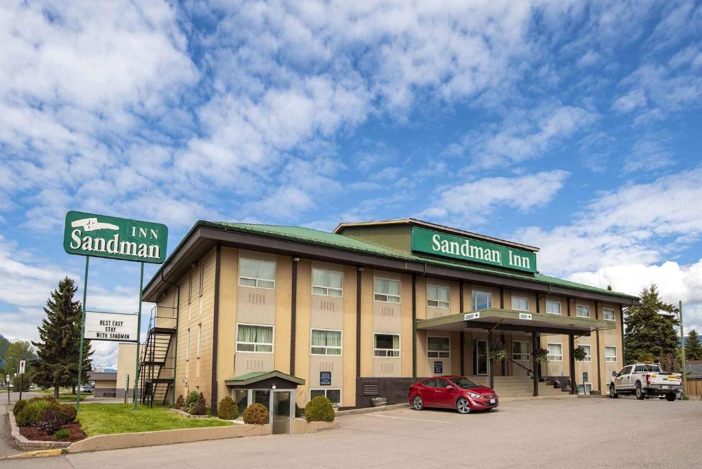 a hotel with a red car parked in front of it at Sandman Inn Smithers in Smithers