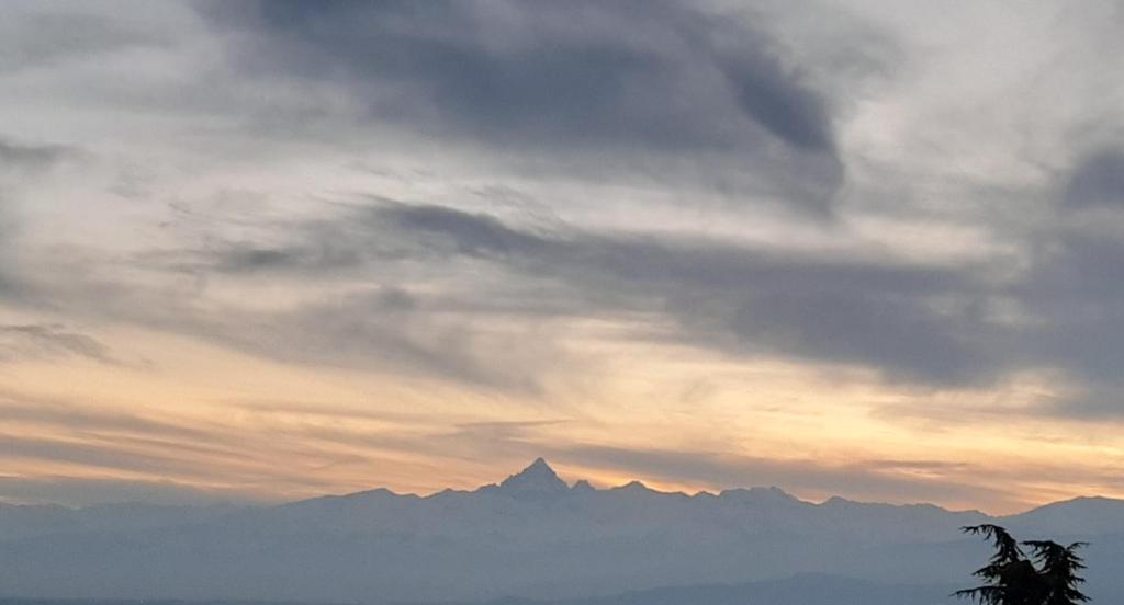 un cielo nublado con montañas en el fondo en Appartamento in villa con vista Monviso, en Piossasco