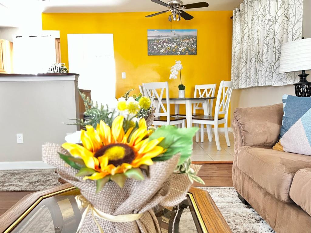 Spacious Ranch Queen Beds 15 min Downtwn في سينسيناتي: غرفة معيشة بجدران صفراء و مزهرية من زهور الشمس