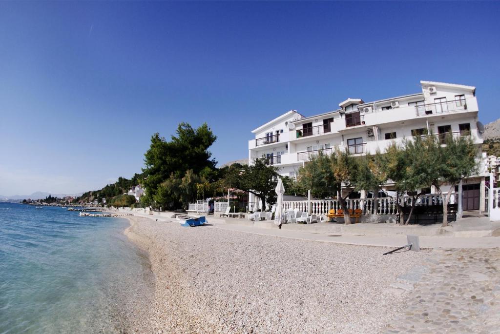 a building on a beach next to the water at Apartments Slava Petricevic in Podstrana