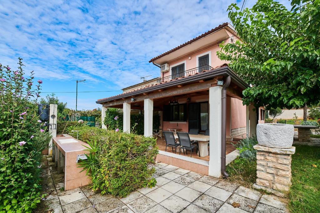 a house with a porch and chairs in a yard at Holiday house with a parking space Valica, Umag - 20533 in Umag