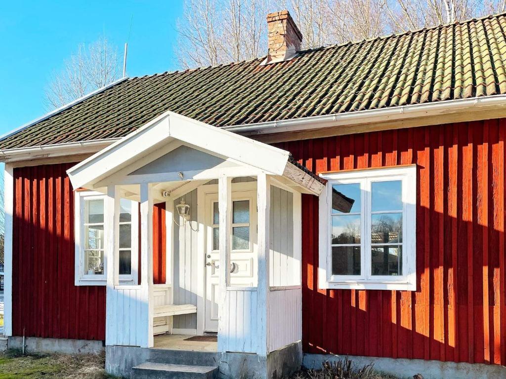 ein rotes Haus mit einer weißen Tür und Fenstern in der Unterkunft Holiday home FORSHEDA II in Forsheda