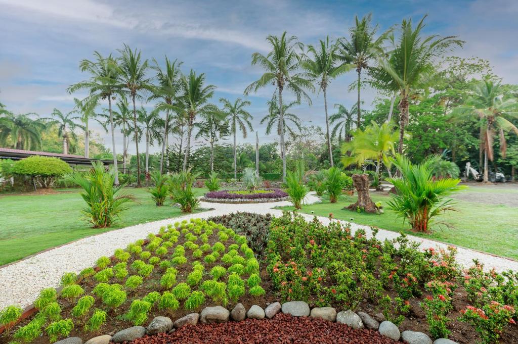 un jardín con seto en un parque con palmeras en Hotel Costa Pacifica, en Esterillos