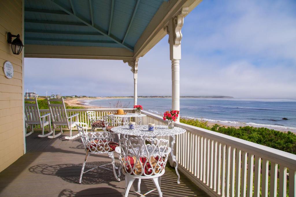 eine Veranda mit einem Tisch, Stühlen und Meerblick in der Unterkunft Avonlea in New Shoreham