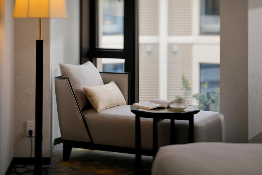 a living room with a couch and a table with a lamp at THE HOTEL SANRAKU KANAZAWA 21th December 2022 OPEN in Kanazawa